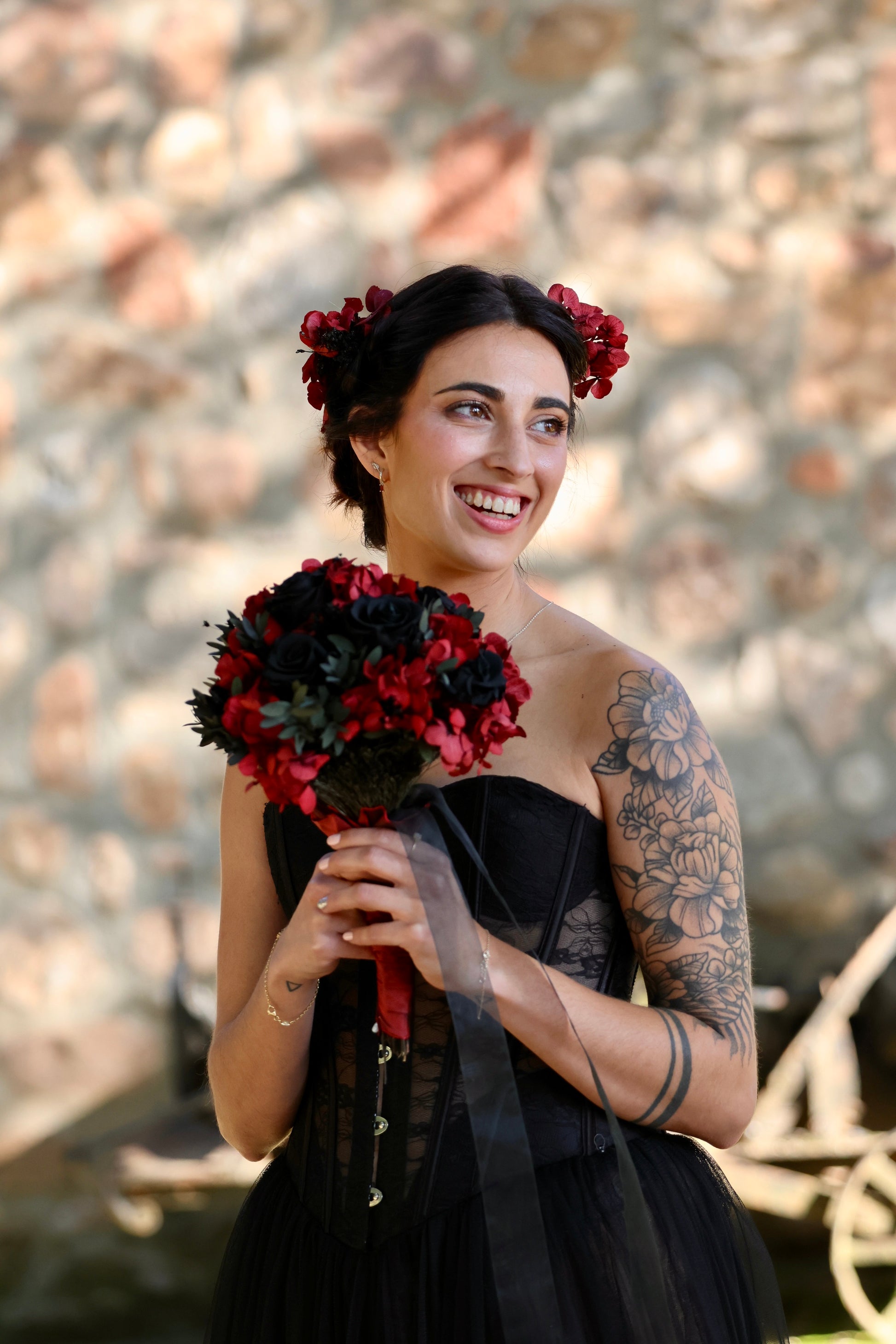 Novia sosteniendo ramo de rosas rojas y negras con hojas verdes oscuras, estilo gótico y sofisticado para boda boho Montseflower