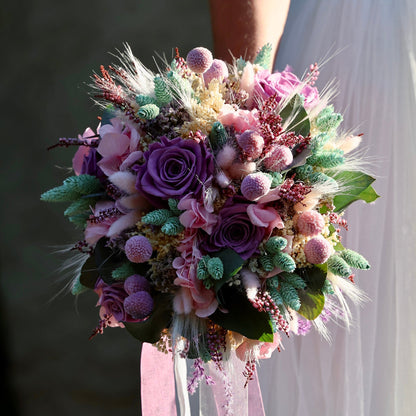 Ramo de novia preservado con rosas moradas y flores secas en tonos pastel con cinta de raso rosa, estilo bohemio romántico