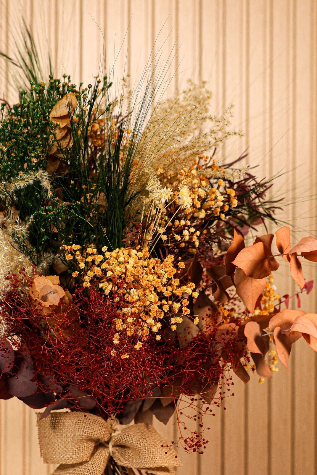 Detalle de flores preservadas en tonos cálidos y hojas verdes del ramo Terracota