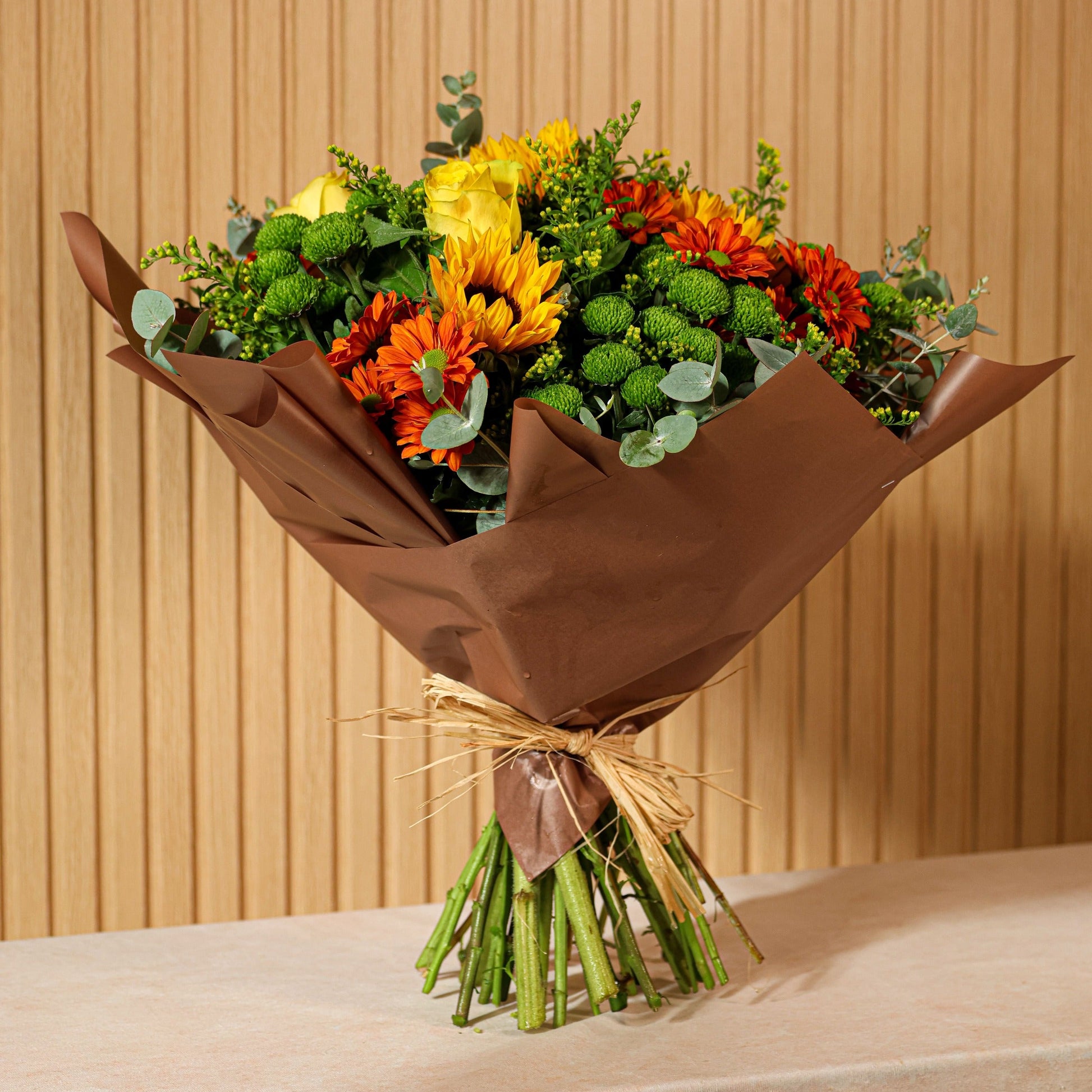 Ramo de flores preservadas Alma de Sol con girasoles, crisantemos naranjas, rosas amarillas y eucalipto verde