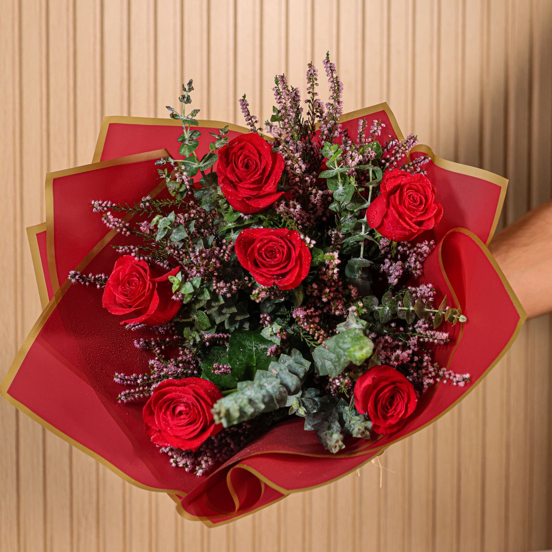 Detalle de rosas rojas con hojas de eucalipto y flores de brezo morado en ramo artesanal de Montseflower