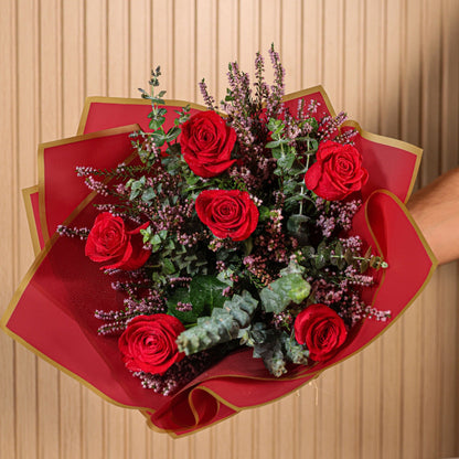 Detalle de rosas rojas con hojas de eucalipto y flores de brezo morado en ramo artesanal de Montseflower