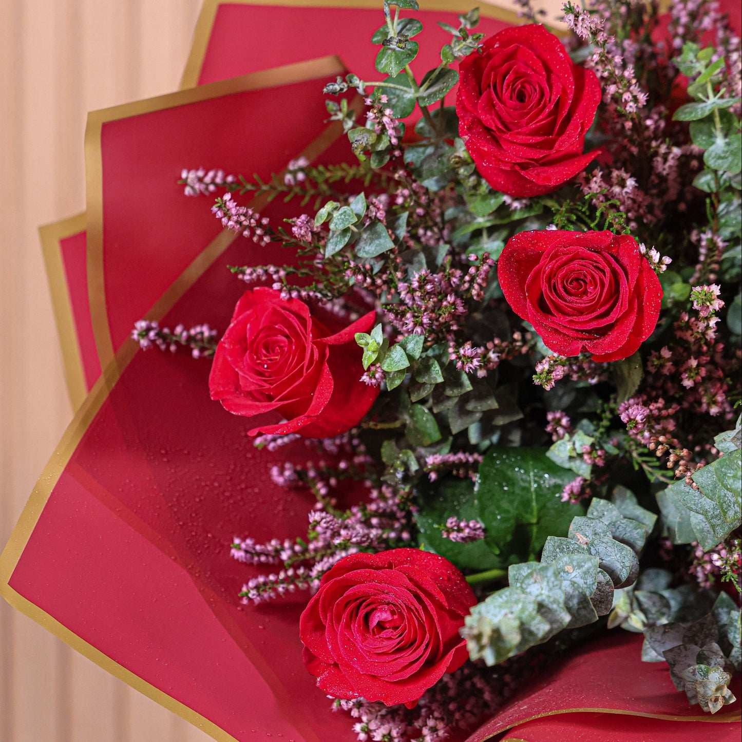 Detalle de rosas rojas con hojas de eucalipto y flores de brezo morado en ramo artesanal de Montseflower