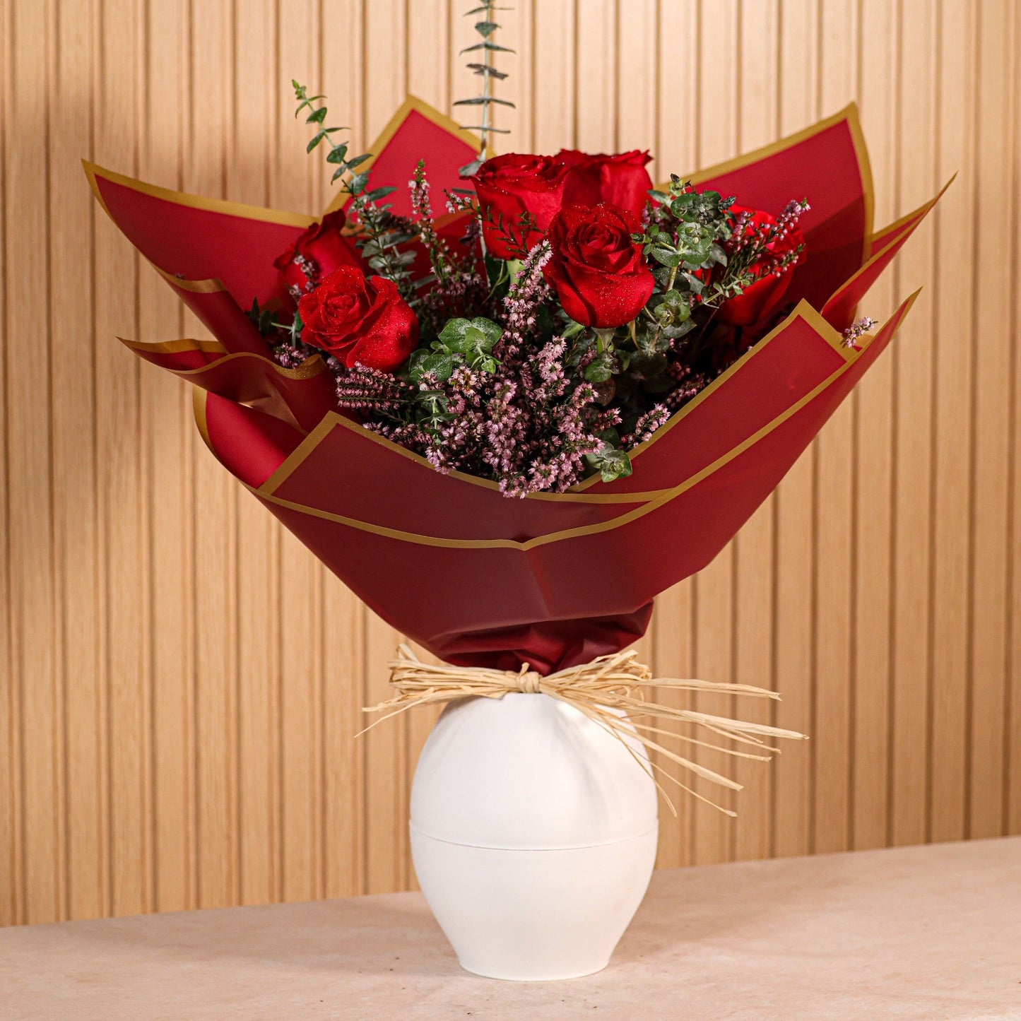 Ramo de 6 rosas rojas con eucalipto y brezo morado sobre fondo neutro, ideal para decoración o regalo floral duradero