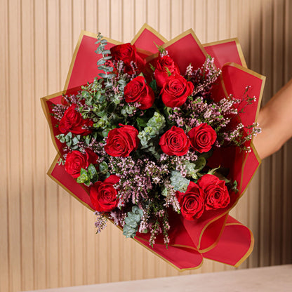 Detalle de ramo de 12 rosas rojas con eucalipto y brezo morado sobre fondo neutro