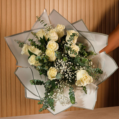 Detalle de ramo de 12 rosas blancas con eucalipto y paniculata sobre fondo neutro