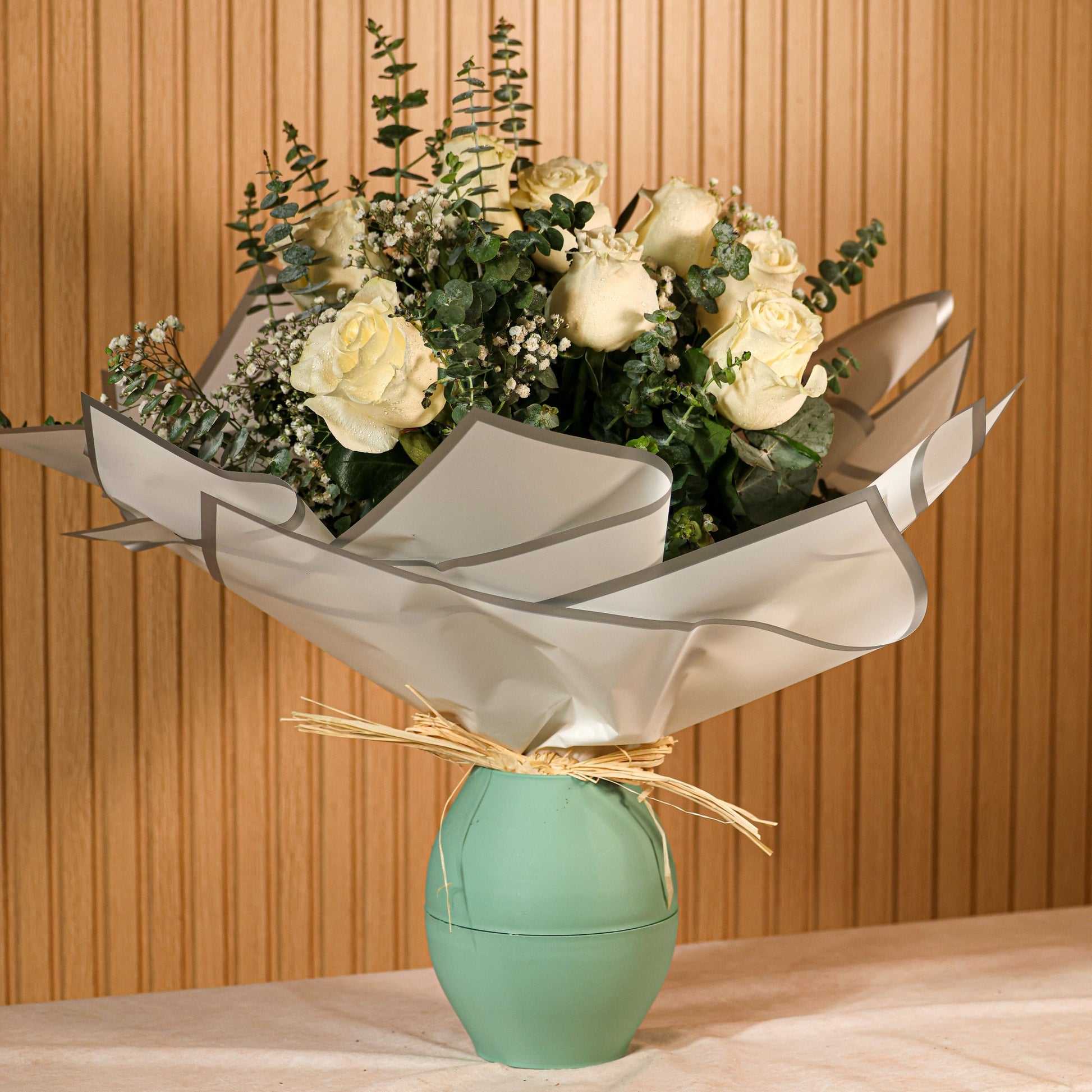 Ramo de 12 rosas blancas con eucalipto y paniculata sobre fondo neutro