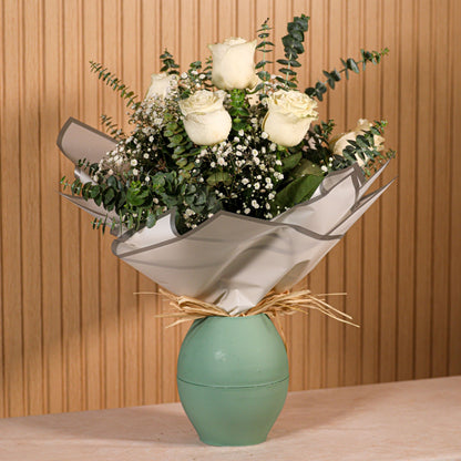 Ramo de 6 rosas blancas con eucalipto y sobre fondo neutro, ideal para decoración o regalo floral duradero