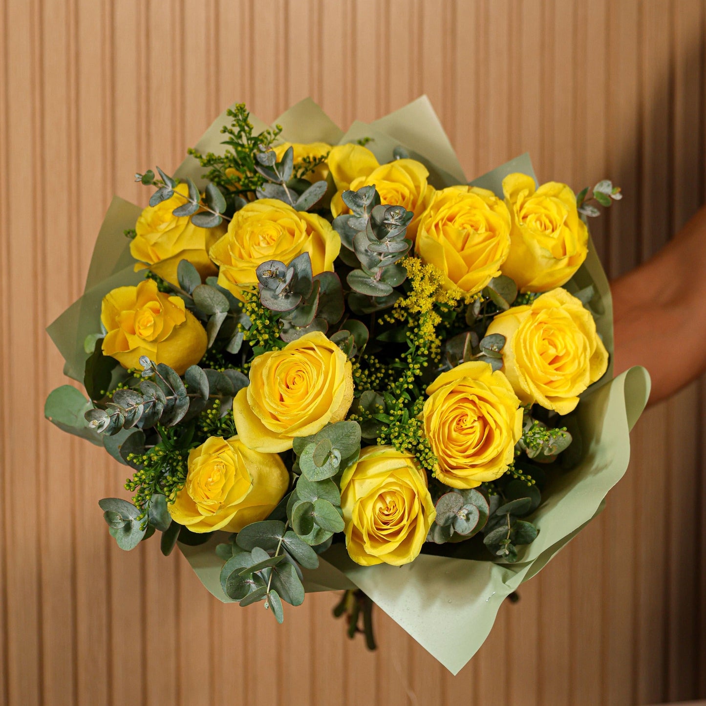 Detalle de ramo de 12 rosas amarillas con eucalipto y brezo sobre fondo neutro