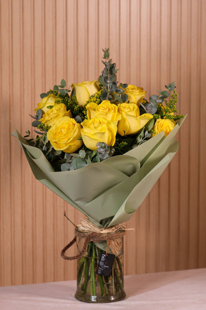 Ramo de 12 rosas amarillas con eucalipto y brezo sobre fondo neutro