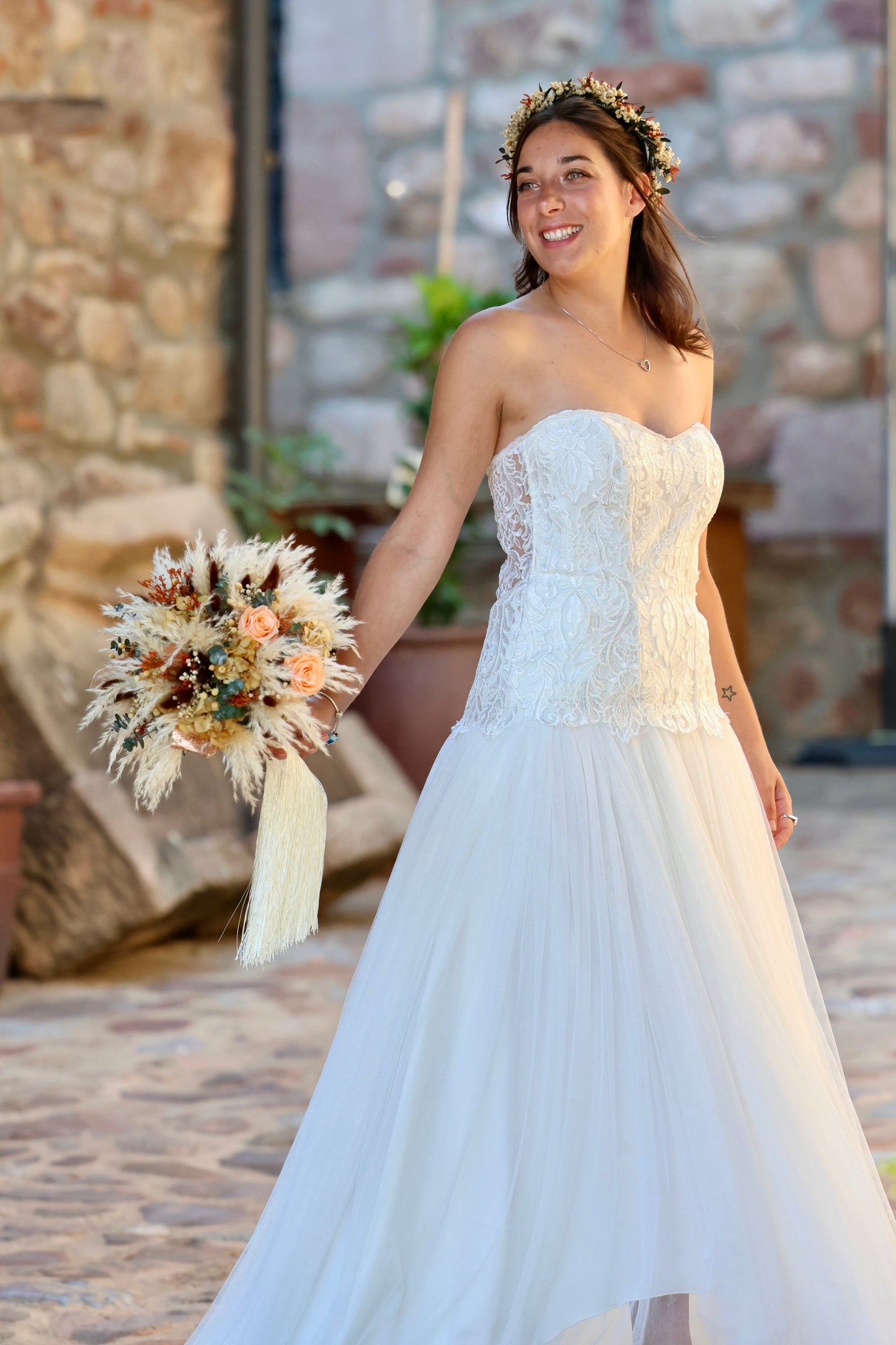 Novia sonriente sosteniendo ramo de flores preservadas en tonos coral y beige, estilo bohemio y natural de Montseflower