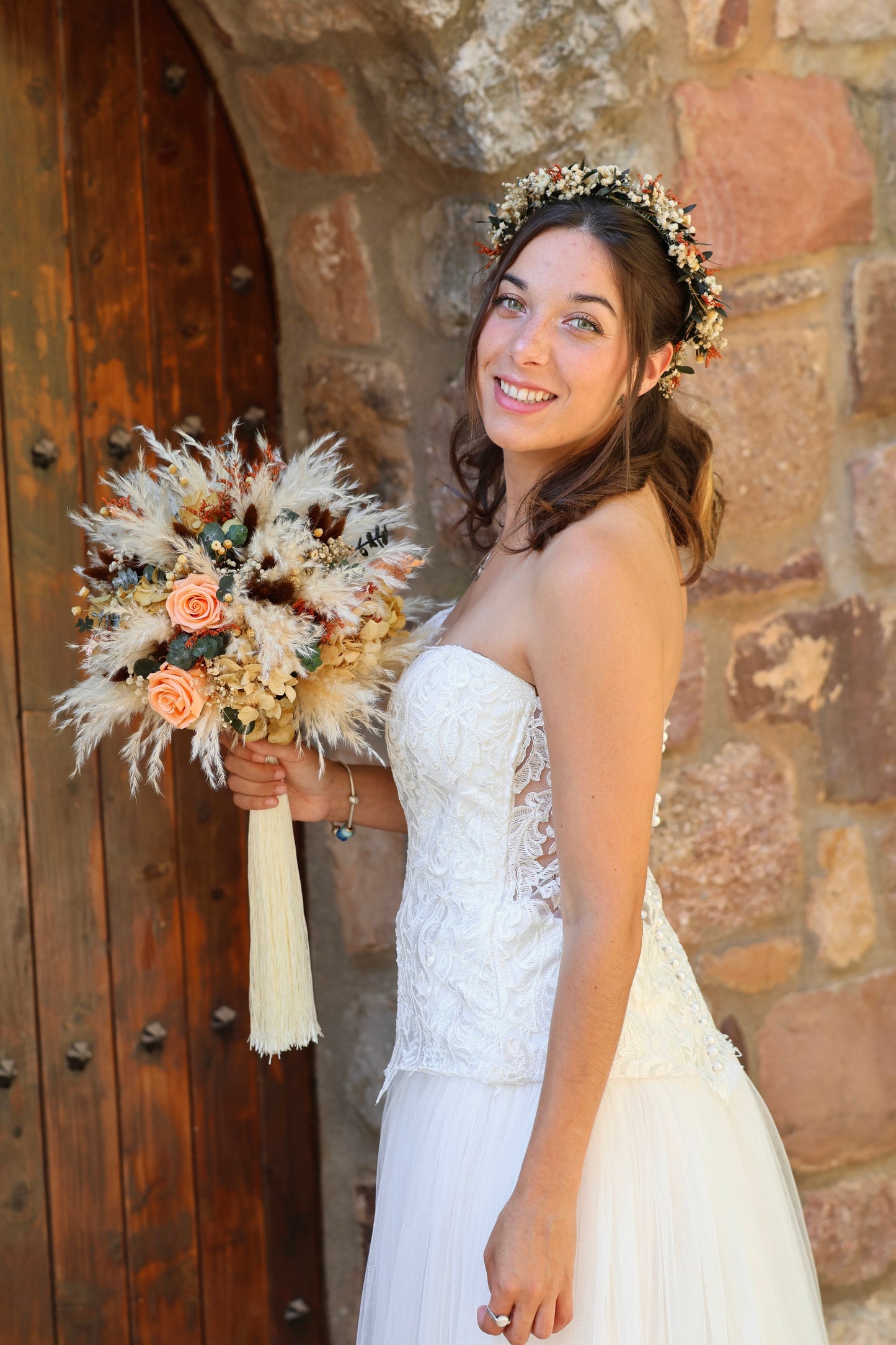 Novia con corona de flores sosteniendo ramo de flores preservadas en tonos coral y beige, estilo bohemio y natural de Montseflower