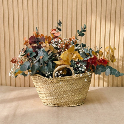 Composición de flores preservadas en cesta de mimbre con tonos ocres, verdes, y blancos